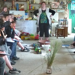 Claudine Delassus, agricultrice du réseau Le Savoir Vert, complète la visite par des explications illustrées (par des échantillons de plantes, des posters, des maquettes...).